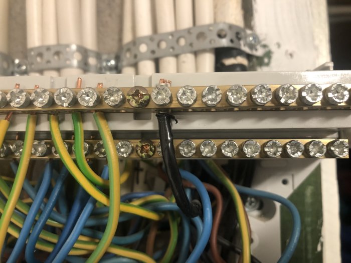 Elektriska ledningar anslutna till en normcentral, med fokus på en svart PEN-ledare.