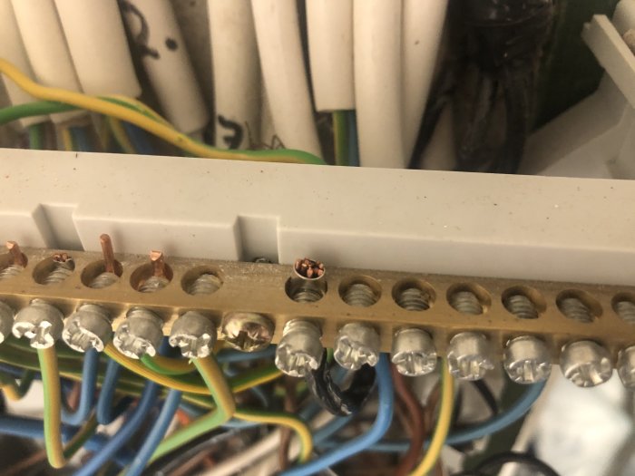 Närbild på en äldre elcentral med synliga koppartrådar och flera inkopplade kablar av olika färger.