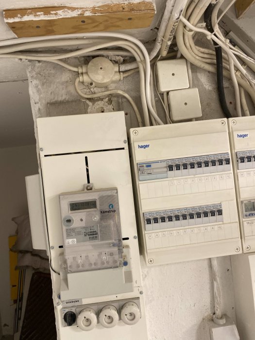 Elektriska kretsar och säkringsskåp med kablar, rörsystem och elmätare på en vägg.