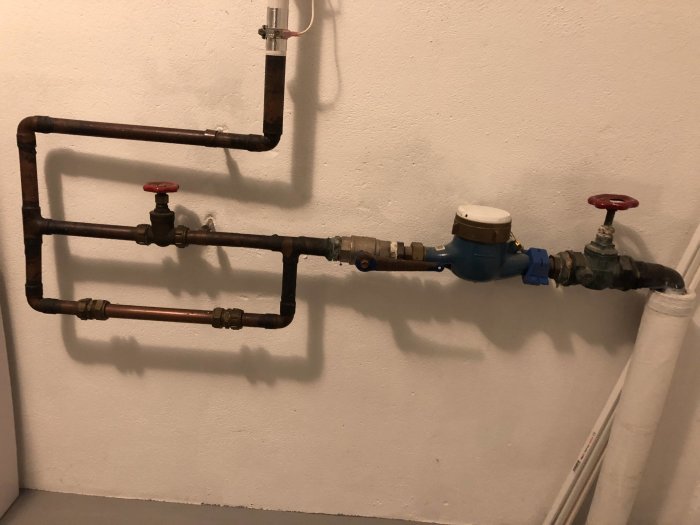 Kopparledningar och ventiler för vatten på en vägg, potentiell utgångspunkt för sprinklersystem.