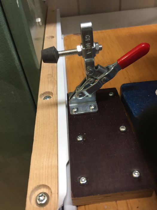 Utdragsskiva låst med spännare, skruvar och metallfästen på arbetsbänk.