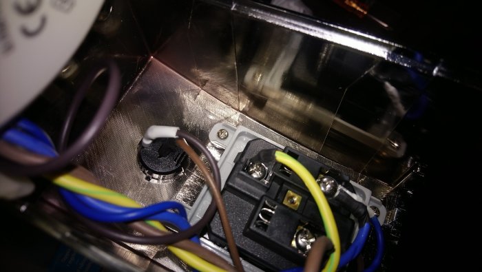 Elektriska ledningar anslutna till en terminal i en apparat, inga tecken på brännskador eller skador synliga.