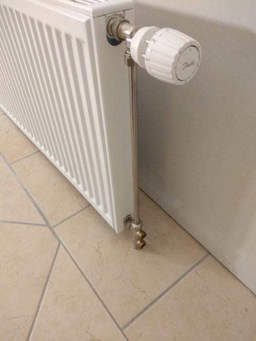 Radiator med termostatventil och kopplingsdetaljer på golvet inklusive förminskningar för rörinstallation.