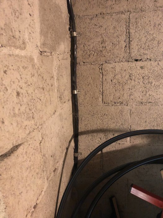 Bild på en kabel markerad med rött streck längs en betongvägg och en hög med kabelrullar i förgrunden.
