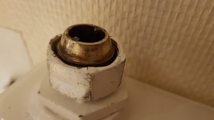 Närbild på skadad returanslutning och deformerad mutter på en sektionsradiator.