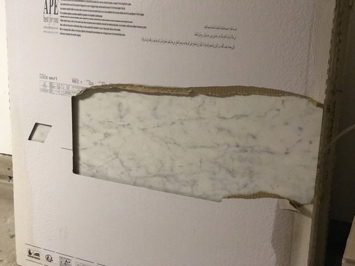Paket med marmormönstrat kakel för badrumsrenoveringen öppnat för att visa kakelplattans design.