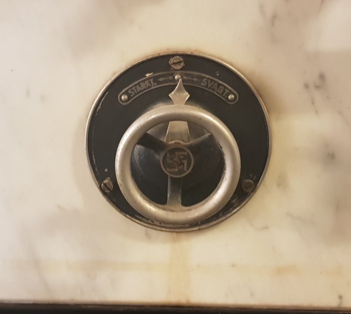 Vintage kontrollhjul på marmortavla med symbol märkt "Stark" och "Svag".