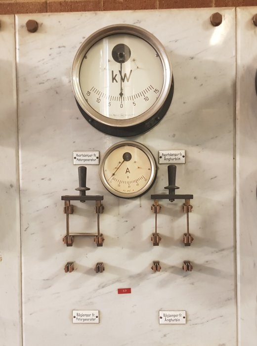 Gammal kontrolltavla med mätinstrument och strömbrytare på marmoryta från tidigt 1900-tal.