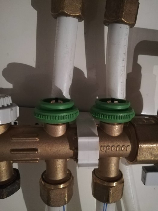Stängt styrdon på ett värmerörssystem med synliga gröna toppar och märket "Uponor".