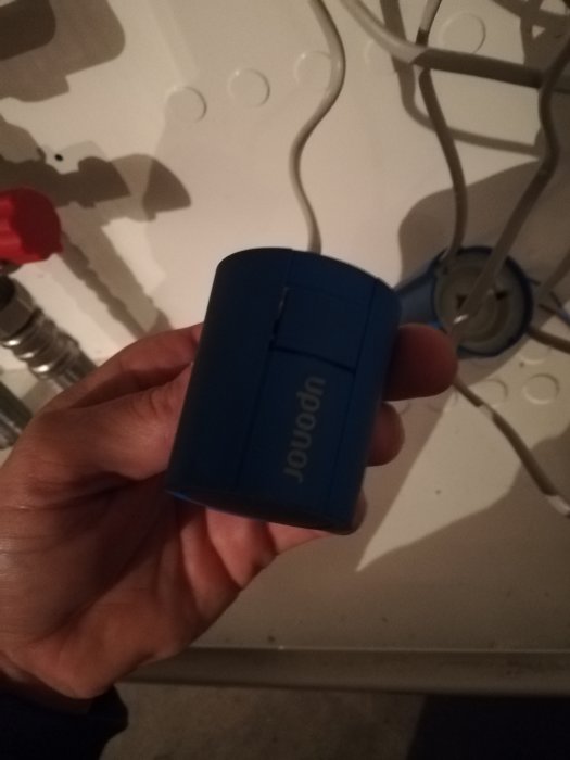 Hand håller ett stängt blått styrdon, inget vitt syns som indikerar att det är öppet.