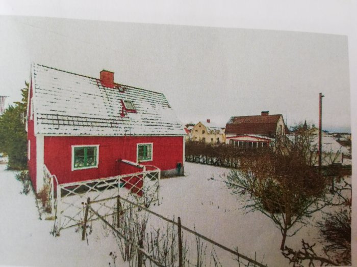 Ett rött hus med snötäckt tak i en snöig trädgård som markerar avslutet på ett utbyggnadsprojekt.