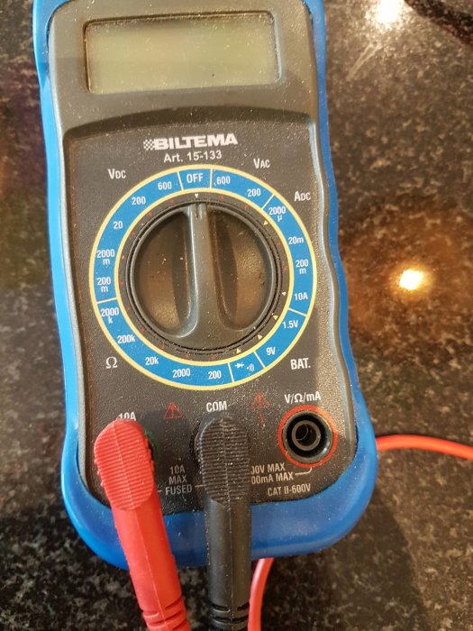 Multimeter inställd för att mäta spänning, med röd och svart testledning ansluten.