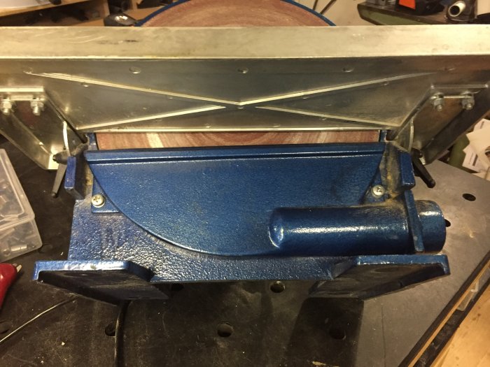 Blåslipmaskin med tätad anslutning och modifieringar för bättre dammhantering monterad på arbetsbord.