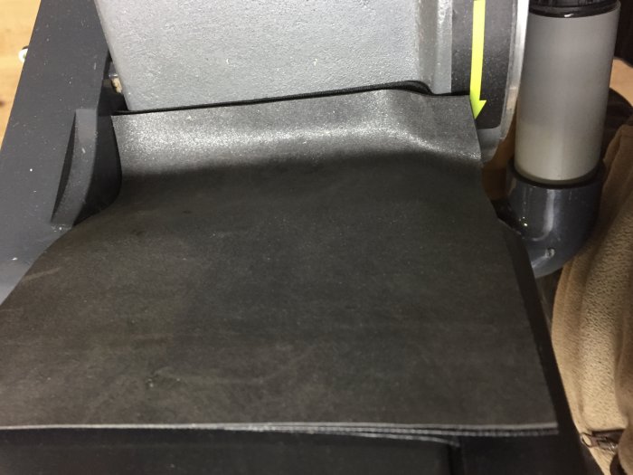 Arbetsbord av en slipmaskin ansluten till sugenheter, med synlig kardborreband och gummiduk för täthet och dammhantering.