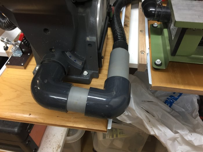 Etablerad dammutsugningsinstallation på en arbetsbänk med anslutna maskiner och utsugsrör.