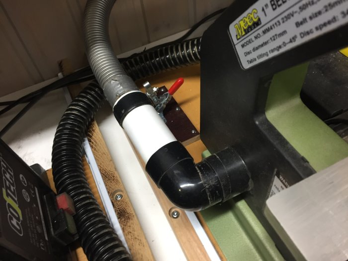 Verkstad med slipmaskiner anslutna till utsugssystem med anpassade rör och kardborrband.