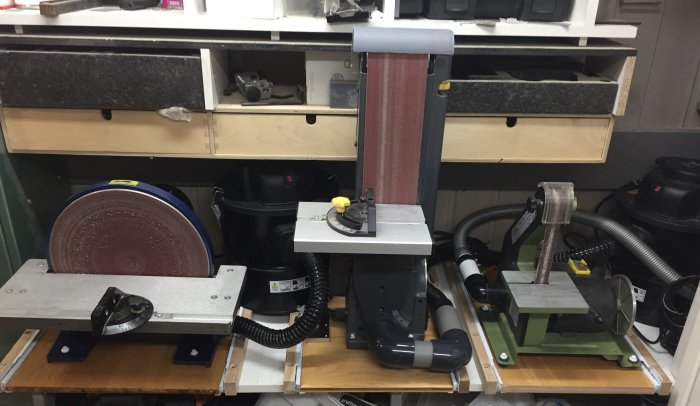 Verktygsvägg med fastskruvade och tätade maskiner, sugslangar och anpassade hörselskydd.