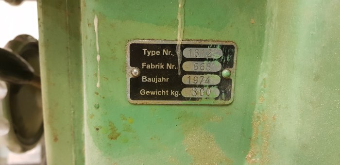Närbild av en identifieringsetikett på en Ulmia 1612 justersåg från 1974, visar typnummer, fabriksnummer och vikt.