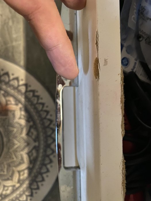 Närplan av en fingerspets som pekar på fuktskada på en vit lådfront från Ballingslöv Soft.