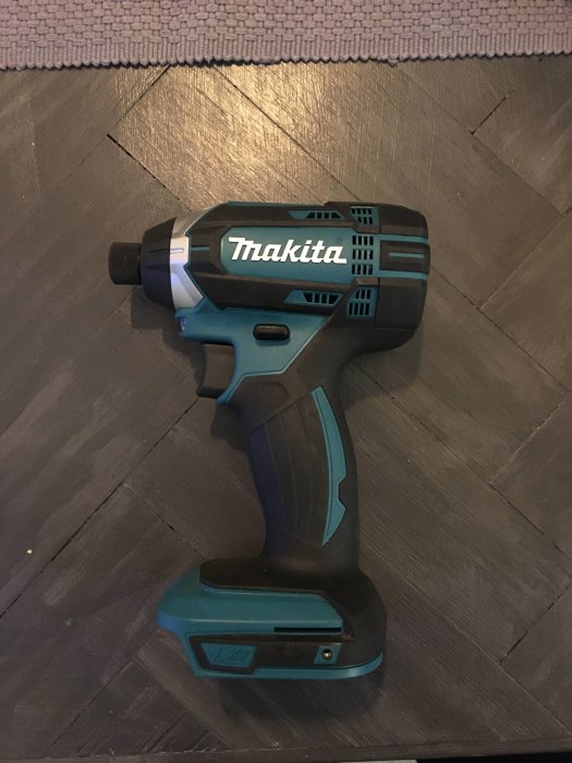 Makita 18v slagskruvdragare ligger på ett trägolv, ser nästan oanvänd ut.