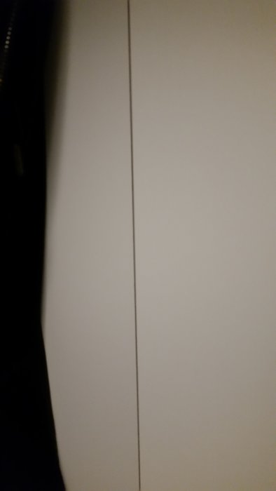 En buktad bakstycke på en vit möbeldel med en synlig skarv i mitten.