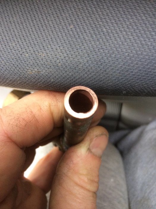 Närbild av hand som håller ett 12mm tjockt kopparrör med synlig godstjocklek på 1,2mm.