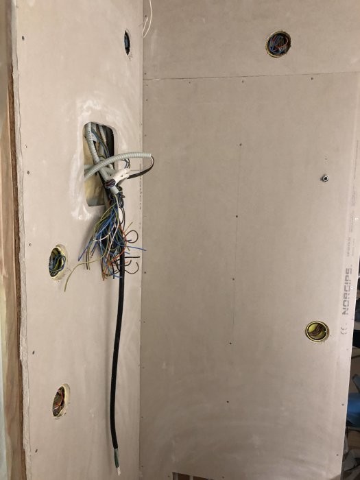 Nyuppsatta gipsskivor med utskärningar för elinstallationer och kablar som sticker ut.