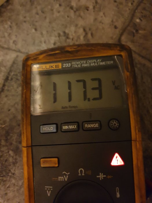 Fluke 233 multimeter visar 117,3 V AC på granitbakgrund.