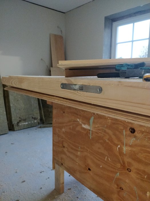 Nysnickrad träport på arbetsbord i ett garage med insatta dörrbeslag, verktyg och material i bakgrunden.