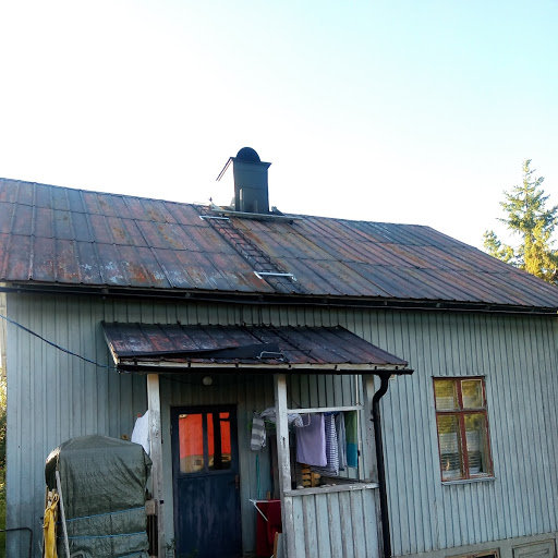 Ett hundraårigt hus med ett renoverat plåttak som visar ojämna avstånd mellan läkter och nocken lutande mot skorstenen.