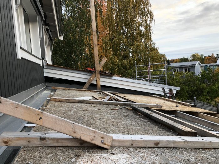 Installation av vindskiva på ett hus med synligt takställningar och målad panel.