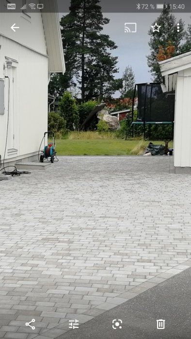 Stenlagd uppfart mellan två hus med ett milt fall mot gatan och kantrader lutande från husen.