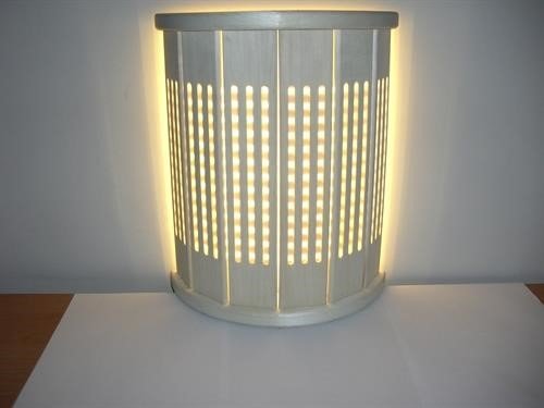 Tänd LED-ljusremsa med varmt ljus bakom en cylindrisk lampa med slitsar.