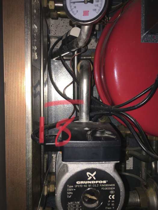 En äldre värmeväxlare med en cirkulationspump modell Grundfos UPS 15-40 och röranslutningar.