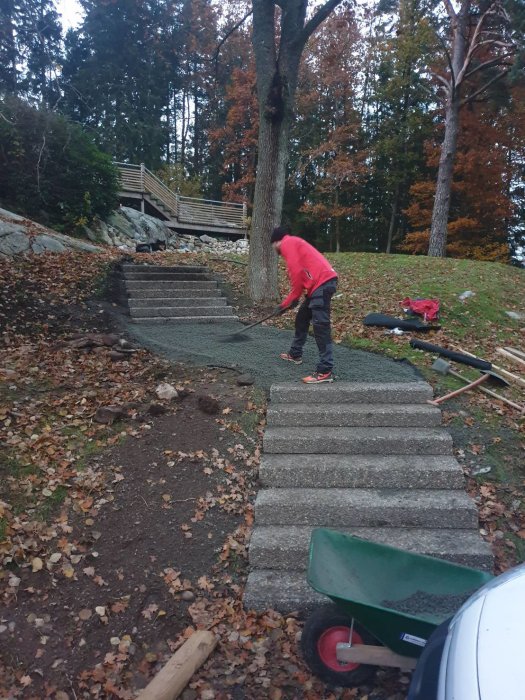 Person arbeter på en trappa utomhus med gamla trappsteg och höstlöv runtomkring.