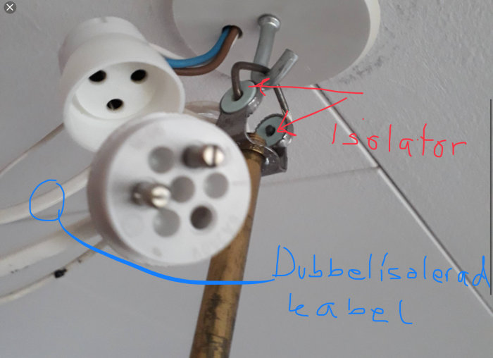 Närbild av en taklampa med öppen kopplingsdosa som visar ledningar, dubbelisolerad kabel och isolatorer.