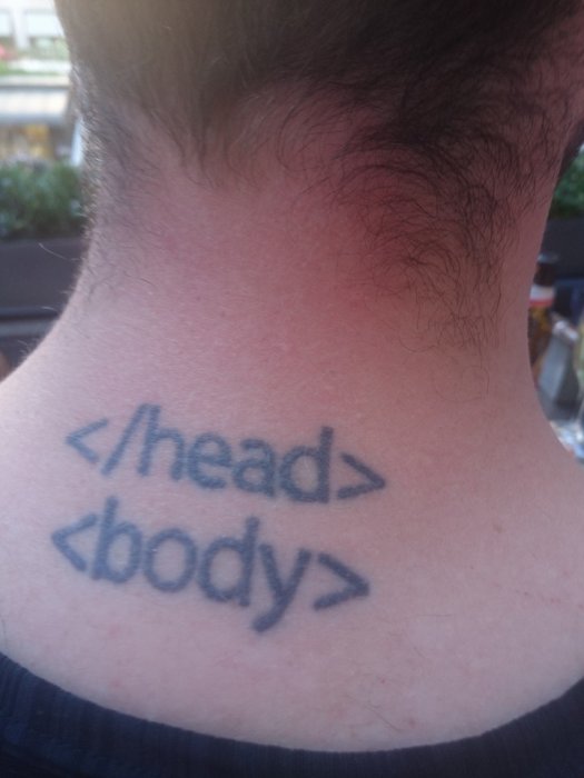 Tatuering på en persons nacke föreställande HTML-taggarna "</head><body>" i svart bläck.