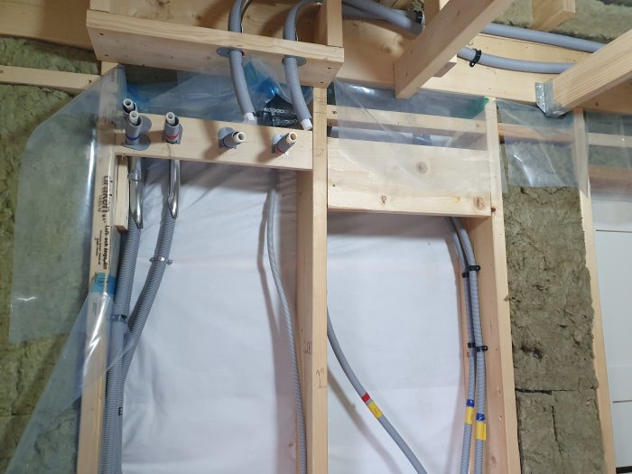 Installation av värmesystem med rördragning och fördelarskåp för golvvärme i ett hus under renovering.