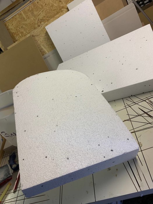 Oskurna cellplastbitar på arbetsbänk för tillverkning av DIY Halloween gravstenar.