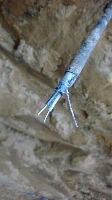 Ca 70 år gammal blymantlad elledning som är oskadad och ser ny ut inuti, exponerad mot en stenbakgrund.