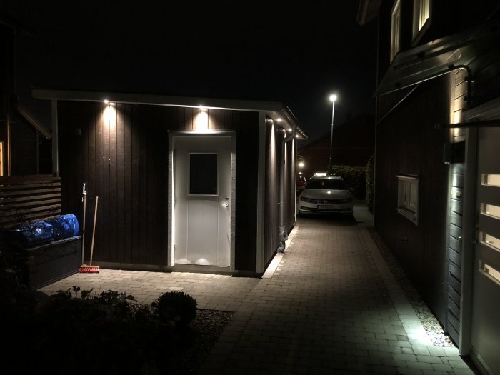 Nyligen installerad takfotsbelysning på ett hus under kvällstid med upplyst gångväg och entré.