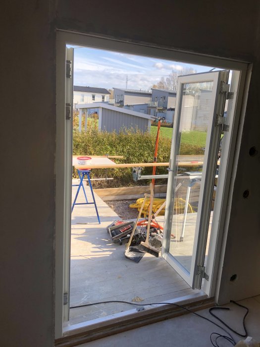 Renoveringsarbete med fönster och dörr, verktyg och byggmaterial synliga, redo för tapetsering.