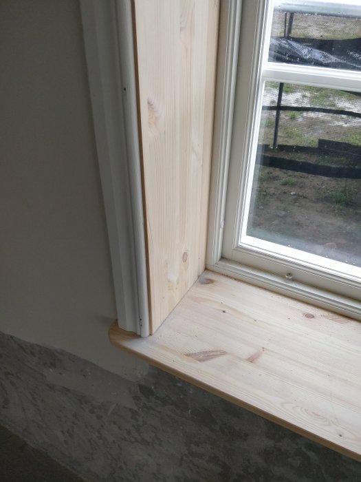 Nykonstruerad träfönstersmyg och fönsterbräda med rundad kant och synlig plywoodshimsning.
