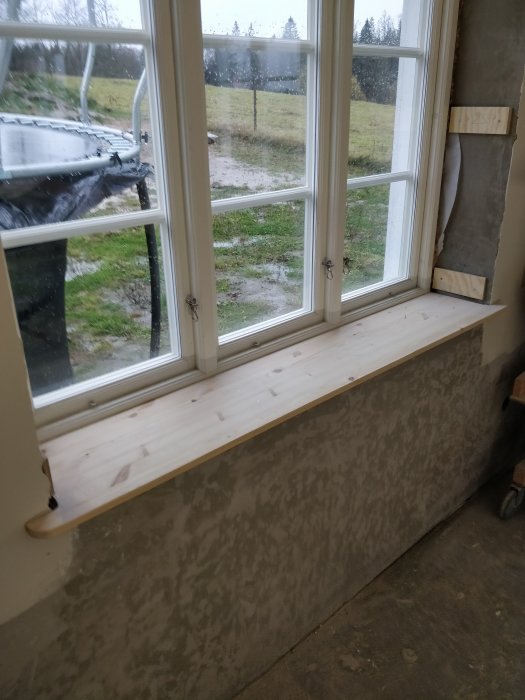 Nyinstallerad fönsterbräda i ett rum med oslipade väggar och verktyg synligt i förgrunden.