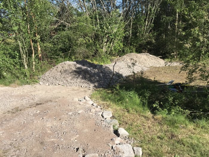 Grushögar på en byggplats i skogsmiljö, troligen förberedelse för en infart.