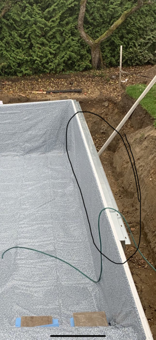 Nyinstallerad thermoflex pool med plåtstomme och synlig liner, omgiven av grävd jord och trädgård.