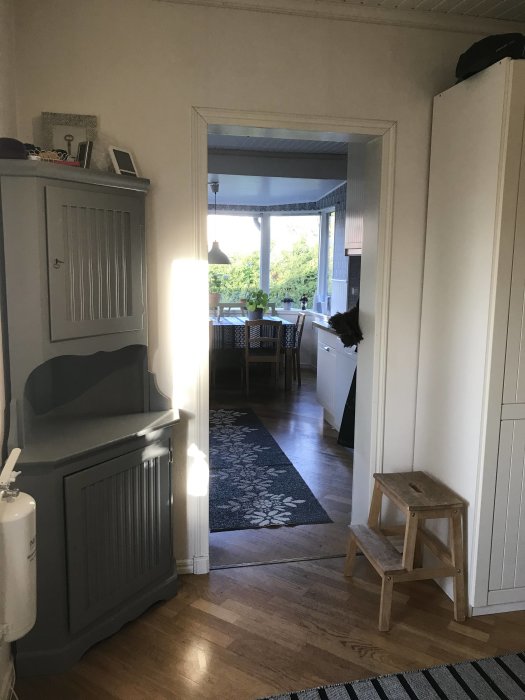 Hallinteriör med garderob och hörnskåp, parkettgolv och öppning mot bakre rum, planeringsutrymme för förvaring och skafferi.