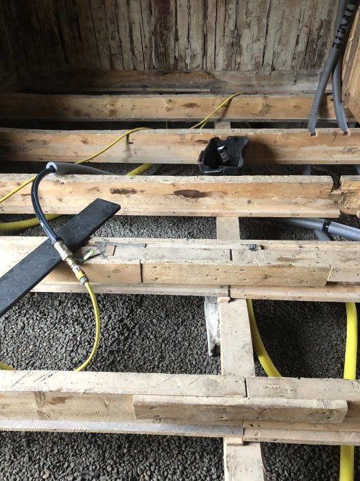 Fläckar på träbjälkar under golvet med synligt isoleringsmaterial och elledningar.