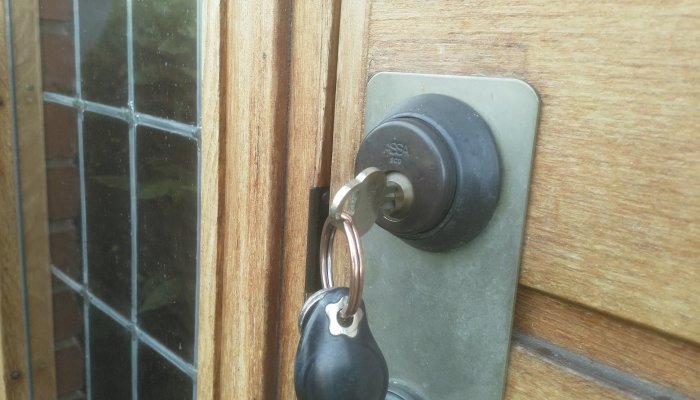 Nyckel i låset av en träförrädörr med fönsterglas och ASSA-låscylinder.