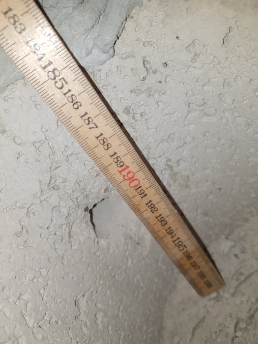 En närbild på ett måttband som visar mätningen av en spricka i en betongyta.